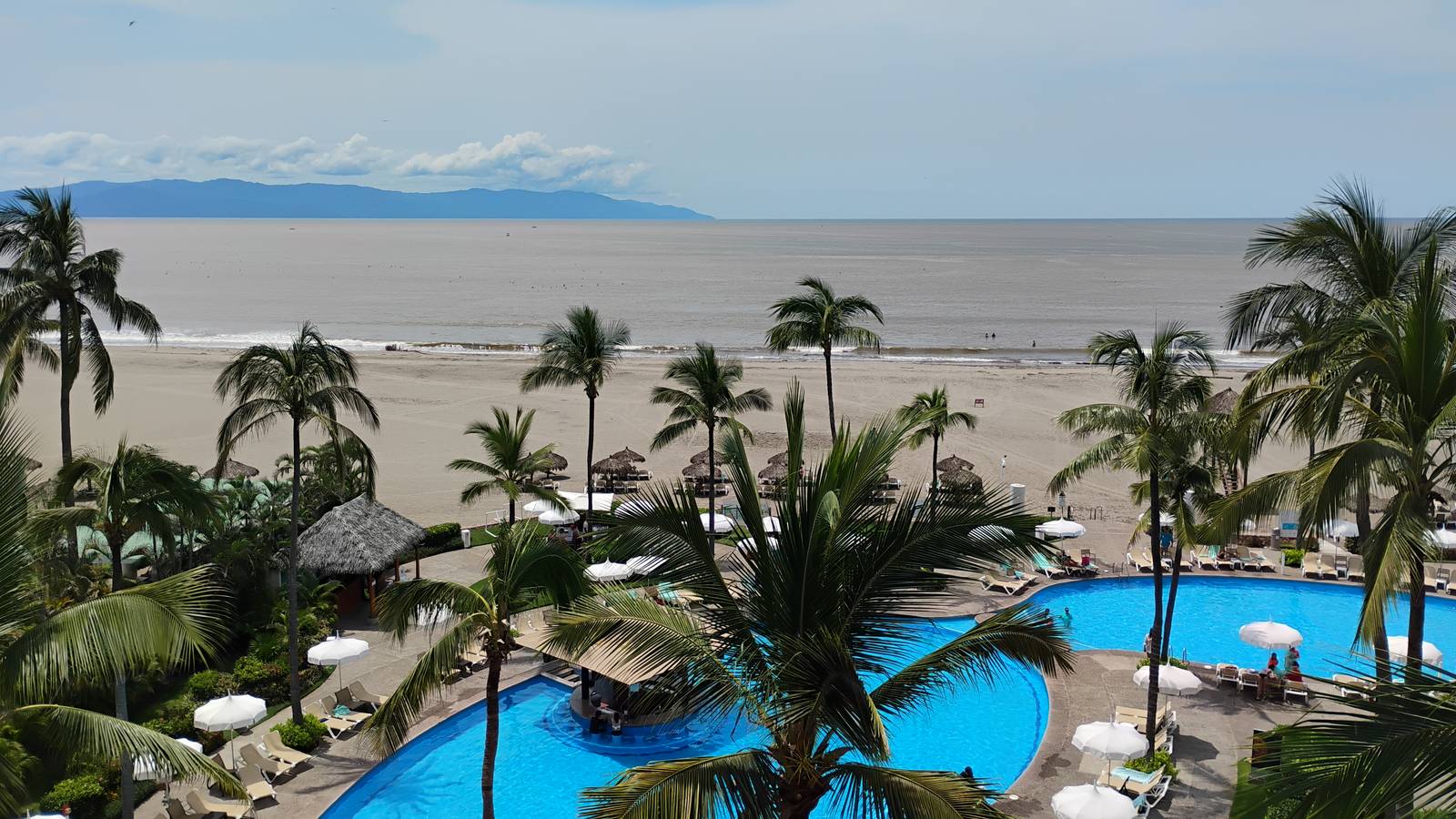 Resort pools, palms and the long beach at Nuevo Vallarta