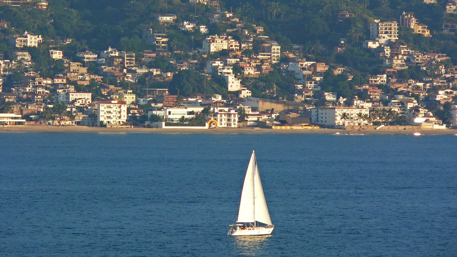 A white sailboat on Banderas Bay in front of Puerto Vallarta